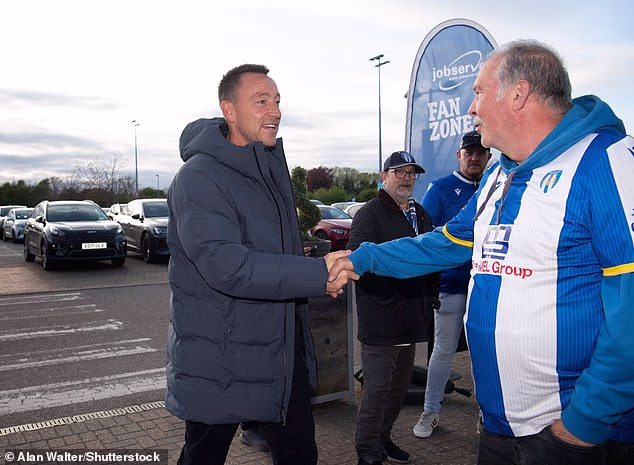 La leggenda del Chelsea John Terry appare alla partita del Colchester United nel mezzo di una “acquisizione da 14 milioni di sterline” – mentre uno dei membri della sua famiglia inizia la partita!